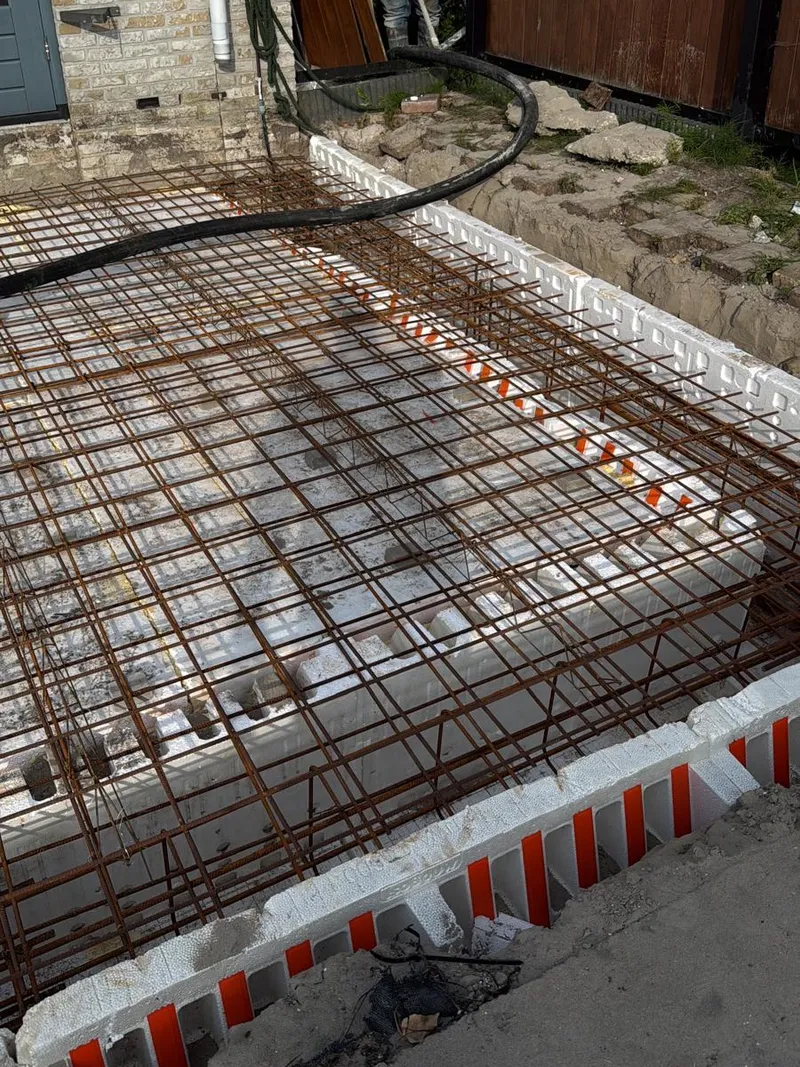 Wapeningsnetten en geïsoleerde bekisting voor de fundering en vloer van een aanbouw, klaar om te storten