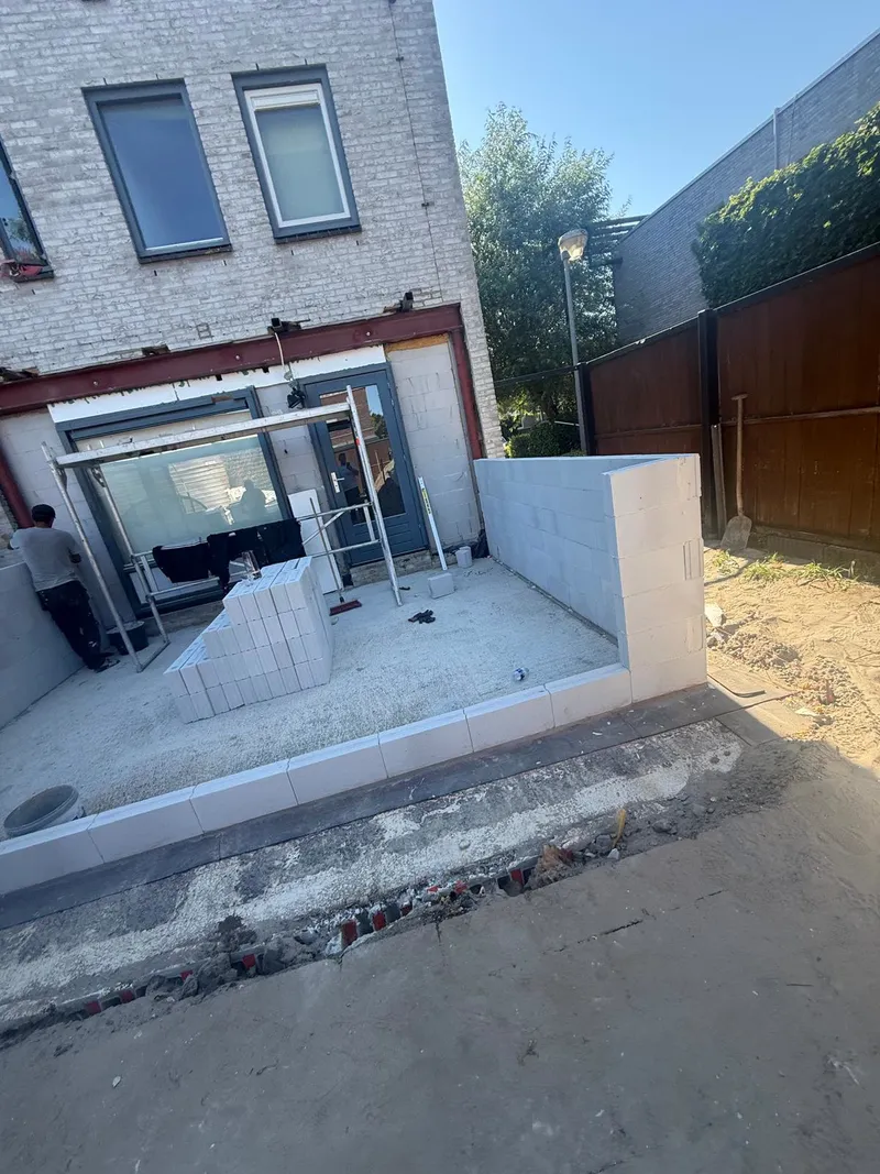 Muren van een aanbouw in witte bouwblokken bij de achtergevel, op de nieuwe betonvloer