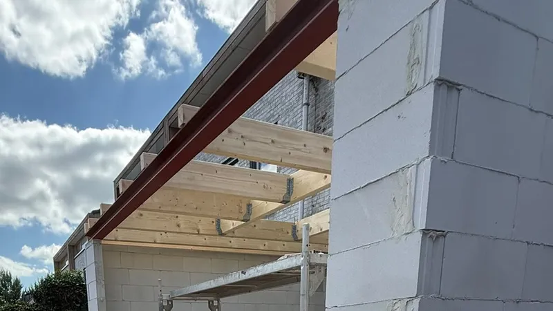 Houten balklaag van het platte dak op de muren en de stalen ligger van een aanbouw