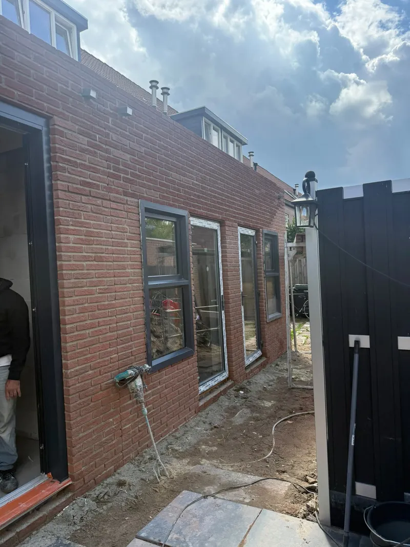 Zijgevel van een aanbouw in rode baksteen met nieuwe ramen en een deur