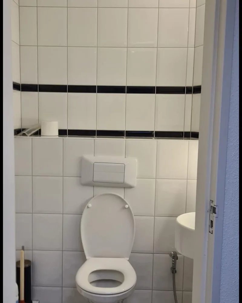 Toilet met inbouwreservoir en bedieningsplaat in een betegelde toiletruimte