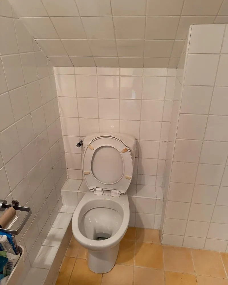Staand toilet onder een schuin plafond, vóór de renovatie naar een hangend toilet