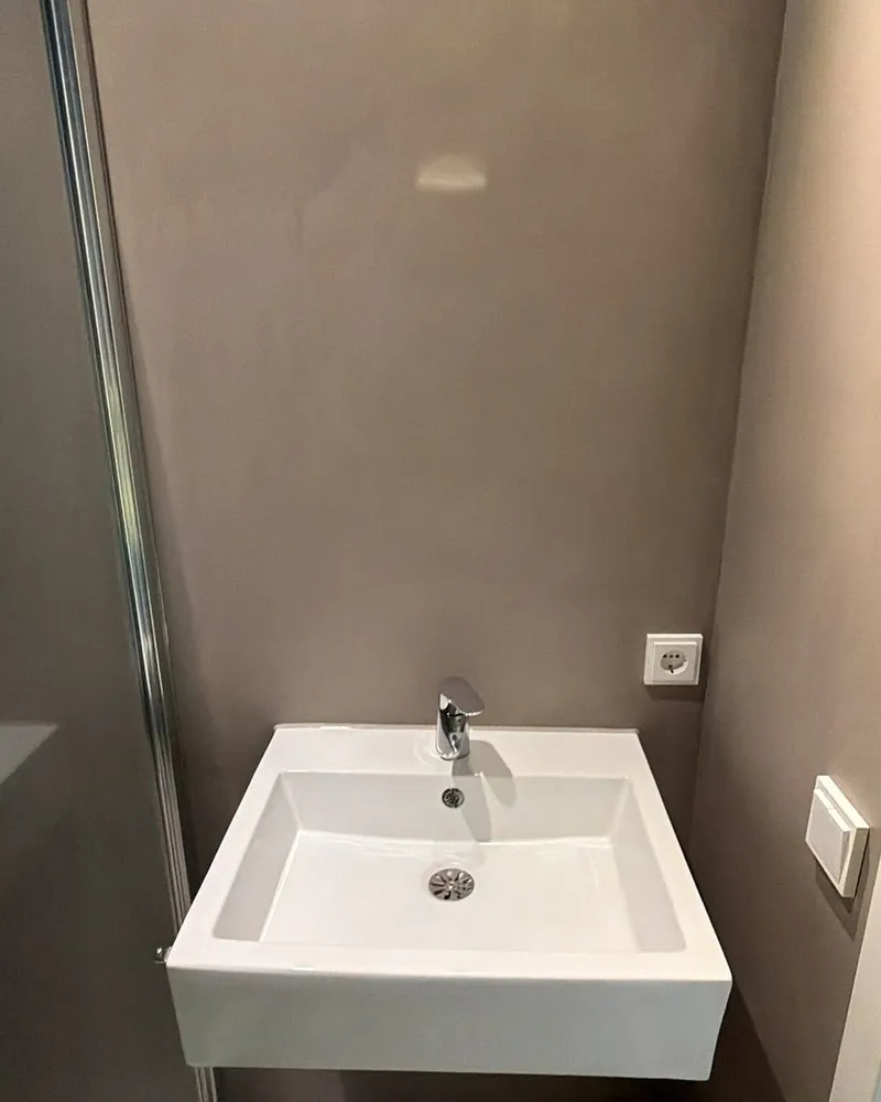 Wastafel met kraan gemonteerd tegen een naadloze badkamerwand