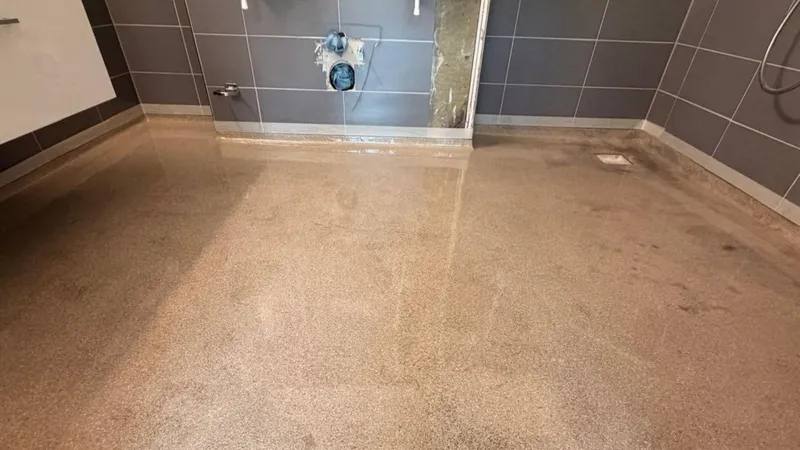 Toiletruimte met grijze wandtegels en de oude vloer, voor het aanbrengen van de vloercoating