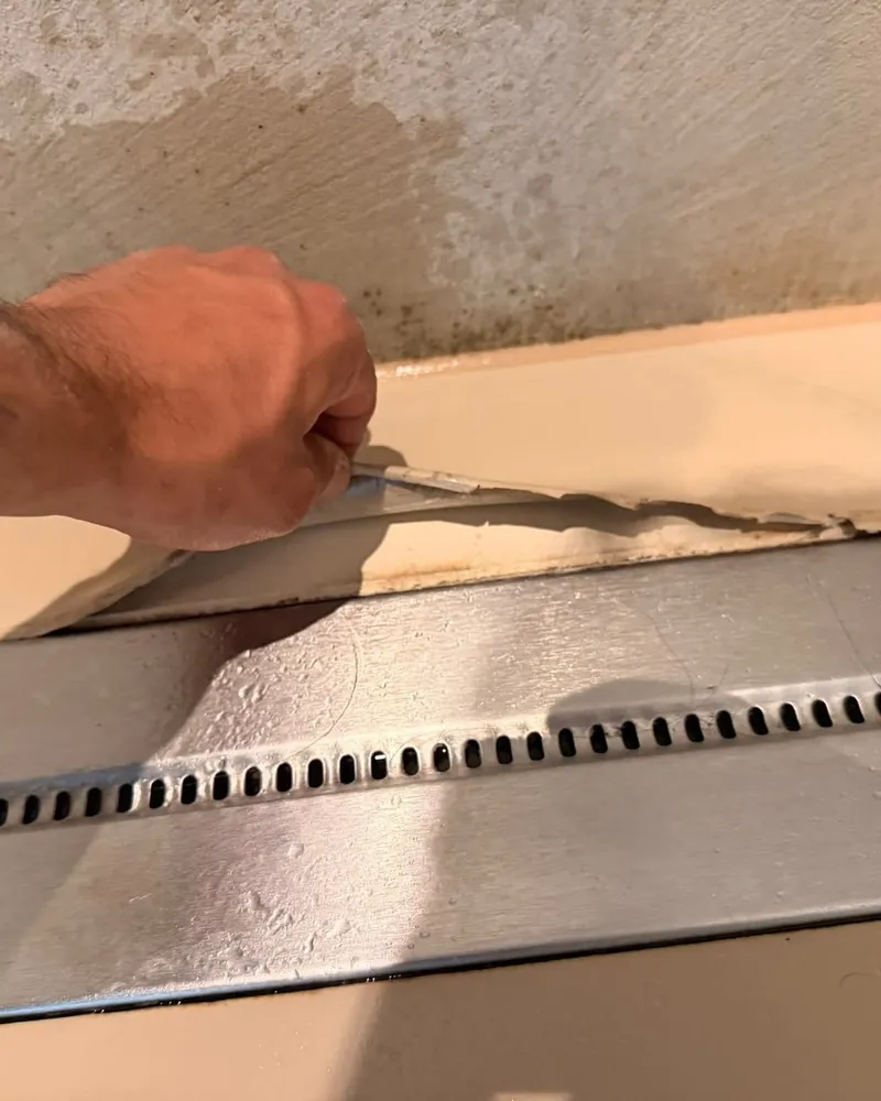 Monteur brengt epoxy vloercoating aan rond de douchegoot