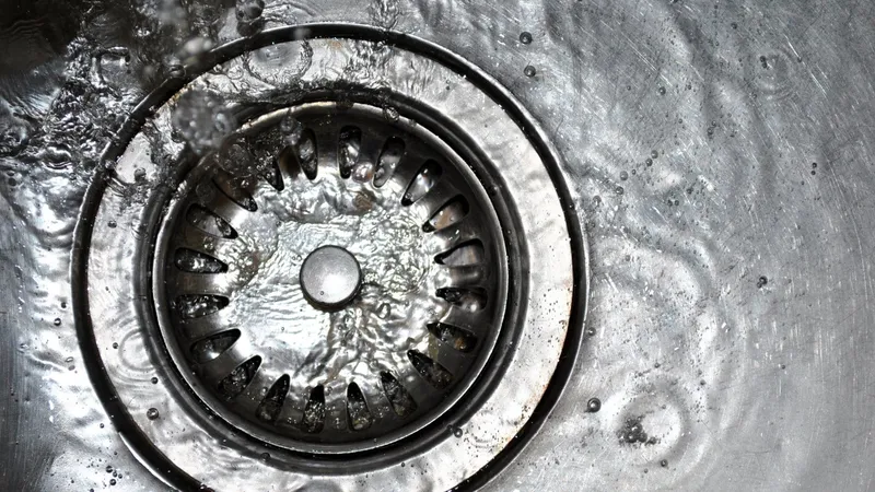 Water loopt weg door de afvoer van een roestvrijstalen gootsteen