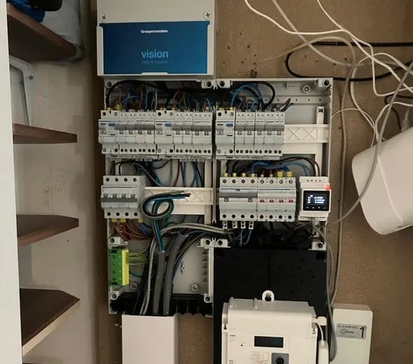 Nieuwe groepenkast in een meterkast naast houten planken, tijdens het aansluiten
