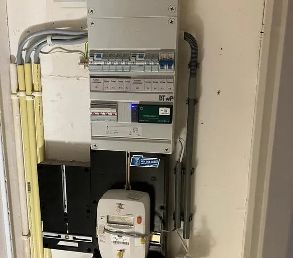 Nieuwe groepenkast met kap en groepsaanduiding boven de elektriciteitsmeter