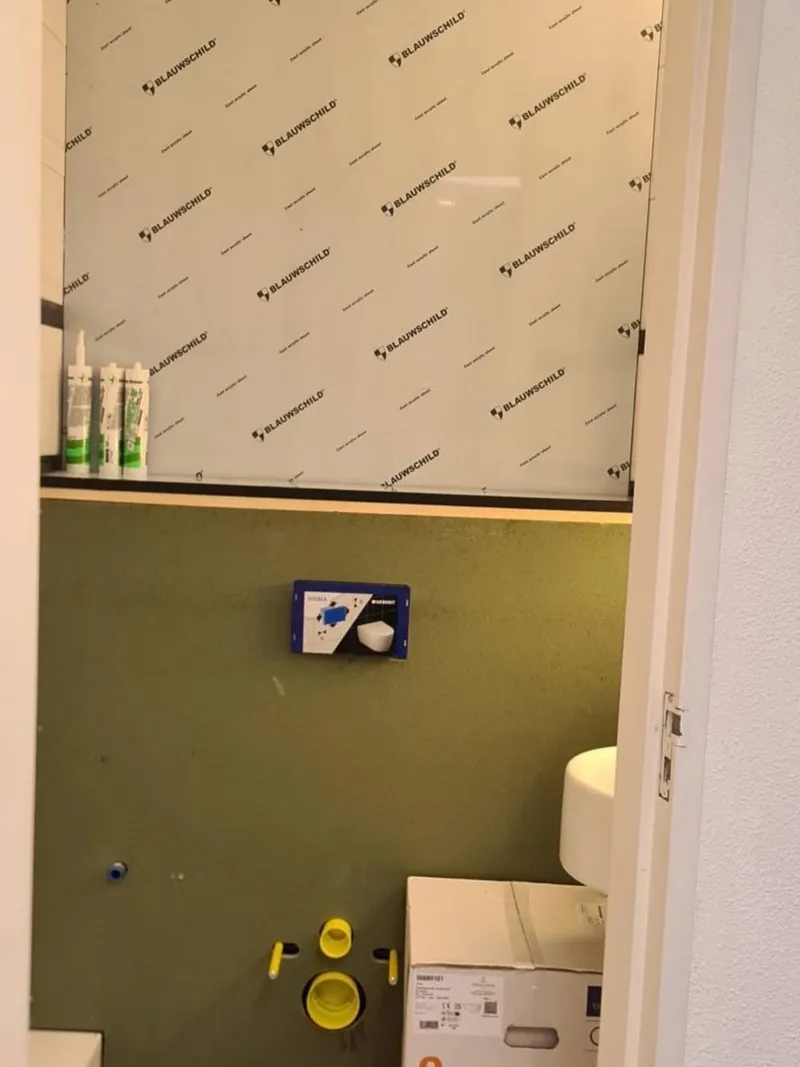 Toiletruimte in aanbouw met ingebouwd reservoir achter vochtbestendige plaat, klaar voor het hangend toilet