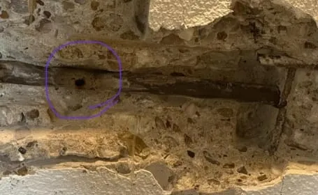 Opengehakte wand met een oude waterleiding, de lekplek met stift omcirkeld