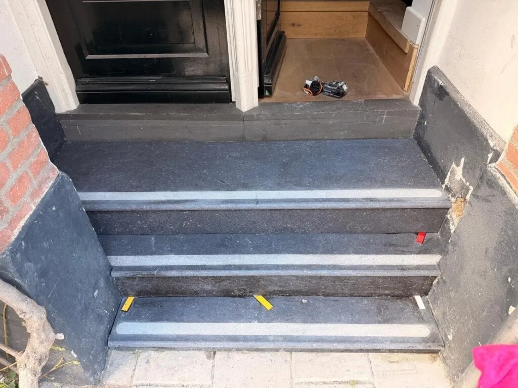 Afgewerkte hardstenen stoep met treden bij de voordeur