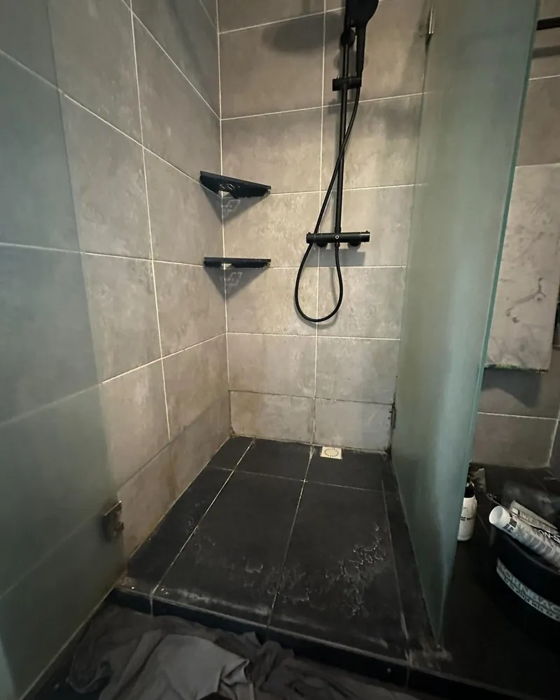 Douche met zwarte thermostaatkraan, twee zwarte hoekplanchetten en een matglazen douchewand