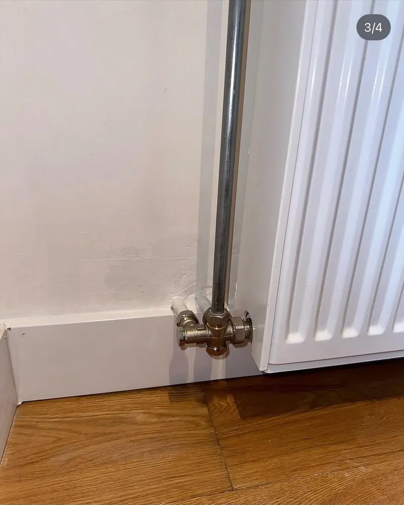 Herstelde radiatoraansluiting op een houten vloer