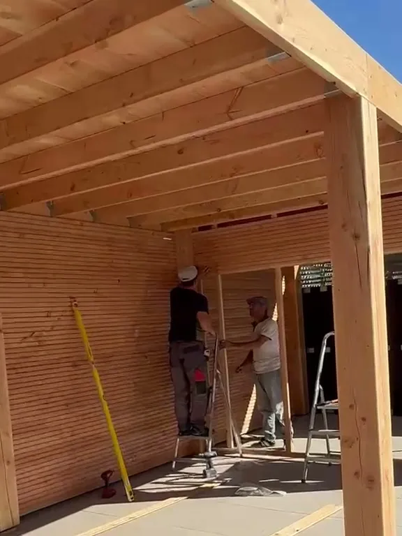 Onderkant van een houten overkapping: dakbalken, een staander en de wandbekleding van houten delen