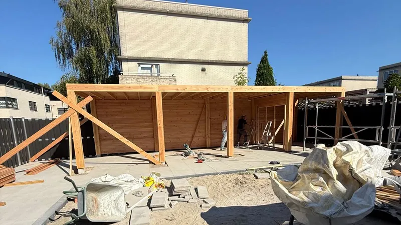 Houten overkapping met staanders en dakbalken op een nieuw terras achter een woning