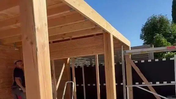 Houten wandbekleding van smalle delen aan de achterwand van een overkapping