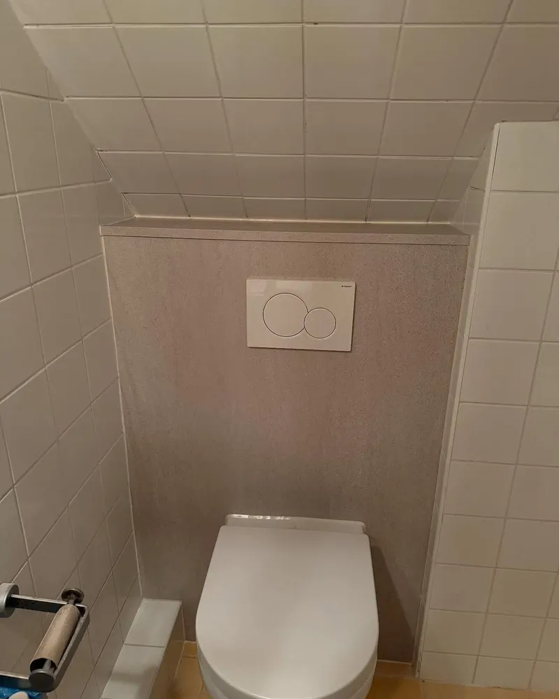 Toiletruimte onder een schuin plafond met nieuw hangend toilet en ingebouwd reservoir