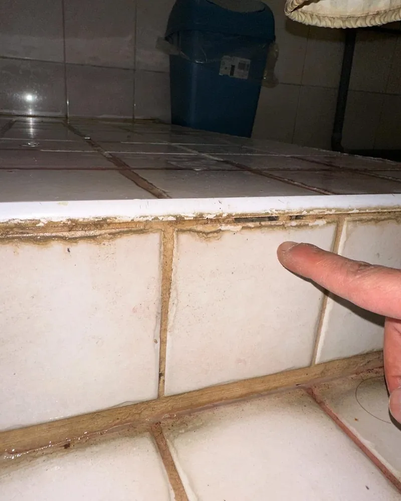 Vervuilde en verkleurde voegen langs een betegelde rand, aangewezen tijdens een inspectie