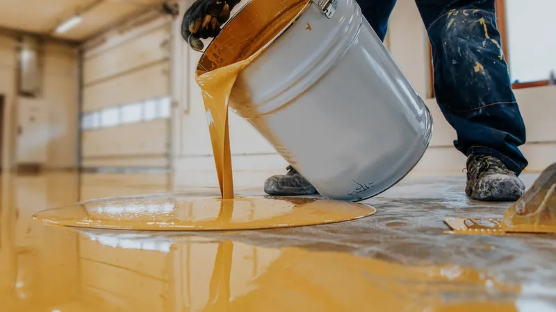 Vloercoating wordt uit een emmer op de vloer gegoten