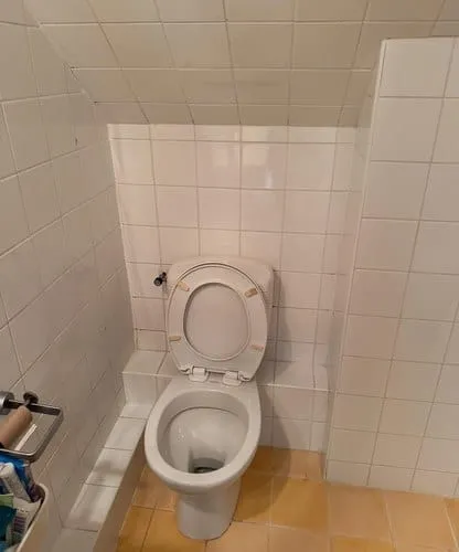 Toiletruimte met schuin plafond vóór renovatie en tegelwerk