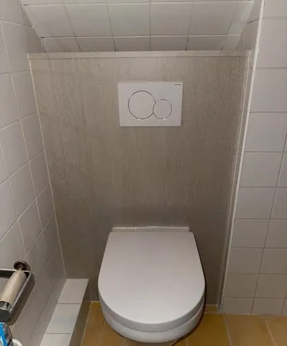 Toilet met nieuw geplaatst wandpaneel na renovatie