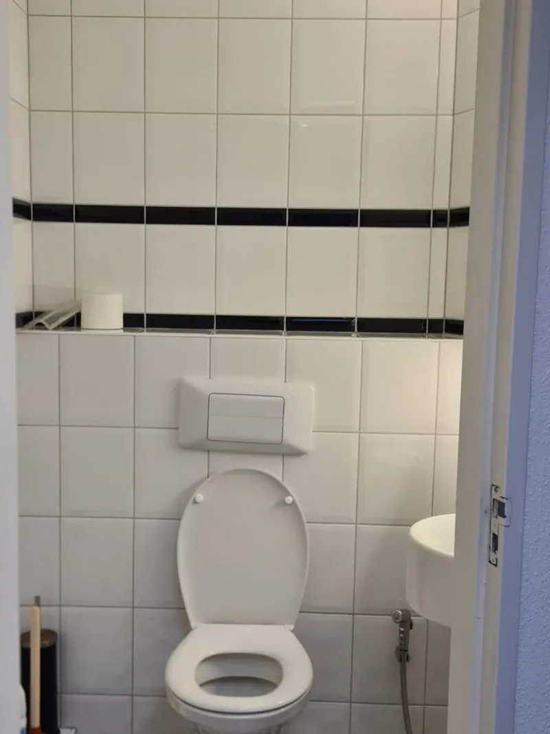 Toilet met inbouwreservoir en bedieningsplaat in een betegelde toiletruimte