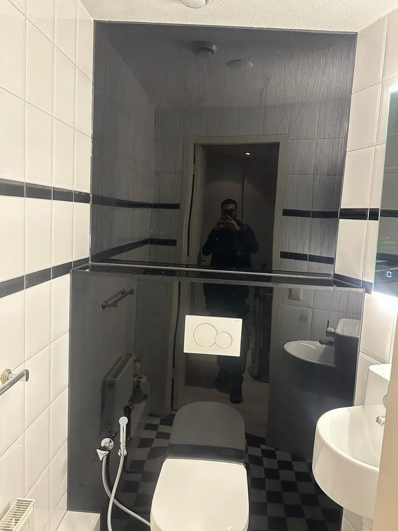 Hangend toilet met bedieningsplaat, bidetsproeier en fonteintje in een toiletruimte met zwart-witte vloertegels