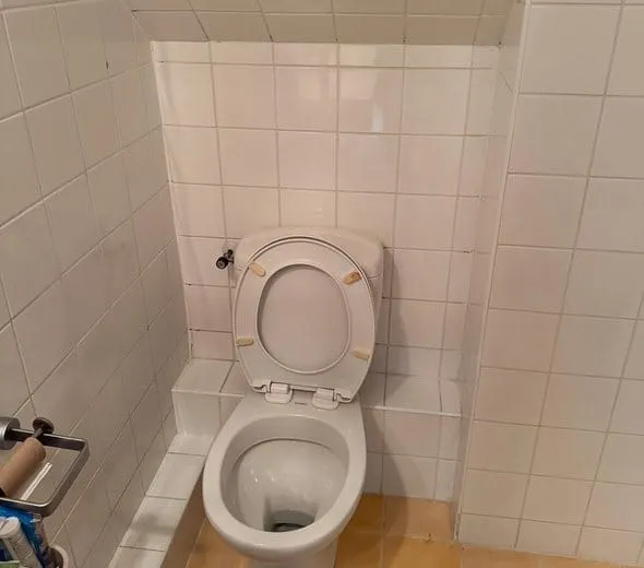 Staand toilet onder een schuin plafond, vóór de renovatie naar een hangend toilet