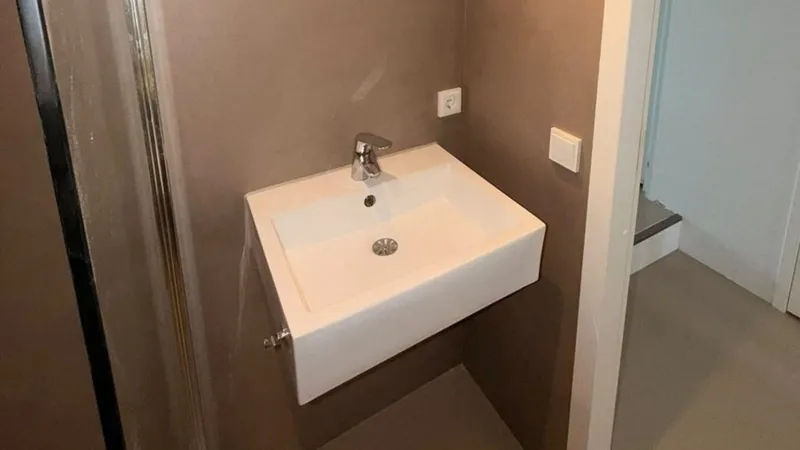 Zwevende wastafel met kraan tegen een naadloze wand