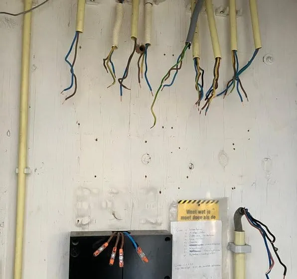 Meterkast waarin de oude zekeringkast is weggehaald; de draden hangen klaar boven de meter